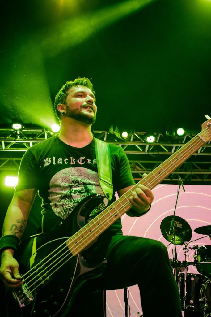 Close-up of a bassist performing energetically on stage during a live music concert.